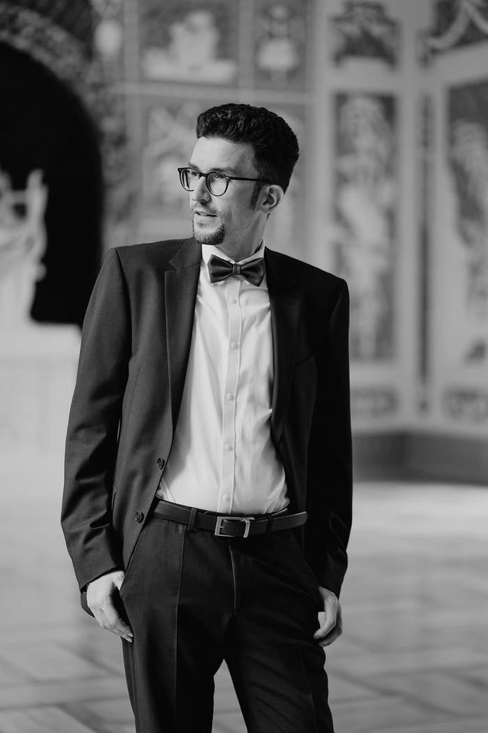 Fabian Heis im Anzug, stehend in einem festlichen Saal.